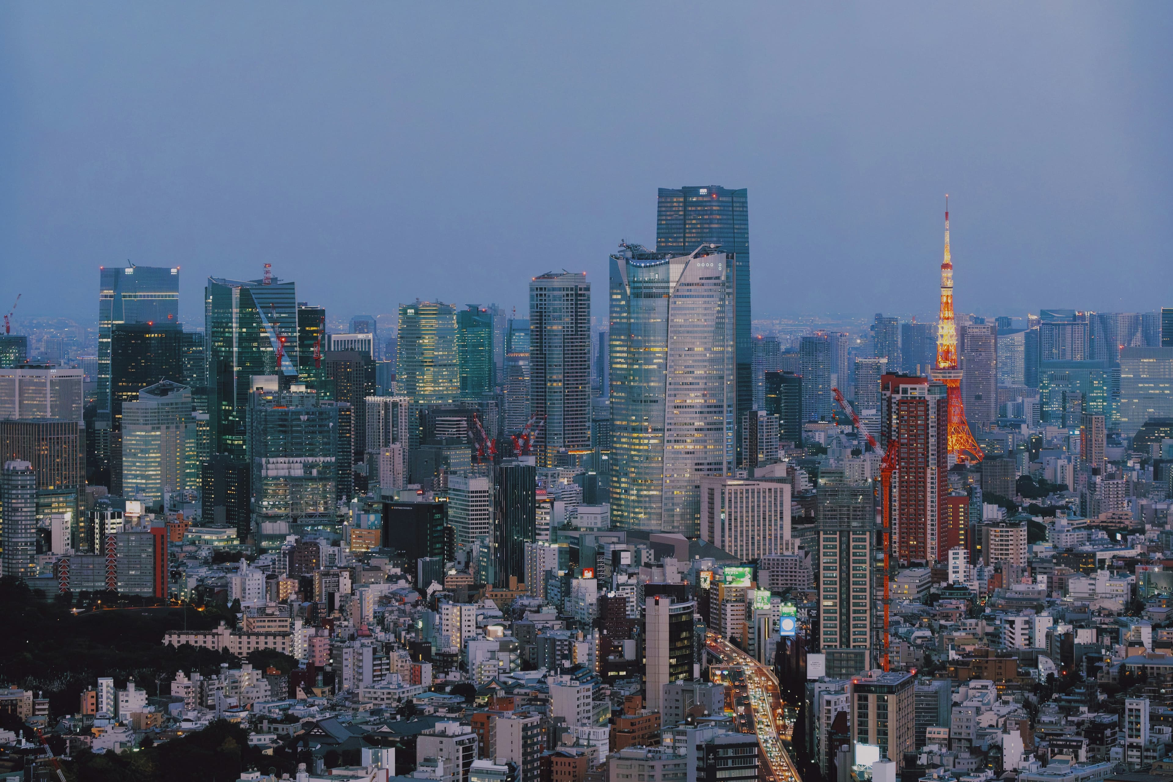 Tokyo city skyline at twilight with glowing skyscrapers and the iconic orange Tokyo Tower.