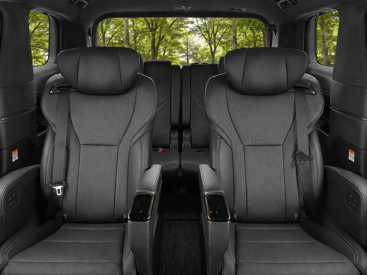 Premium black leather captain's chairs in a luxury vehicle overlooking a lush green forest.